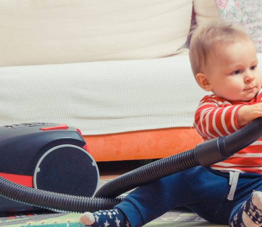 Baby spielt mit dem Staubsauger