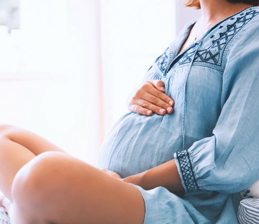 schwangere Frau hält ihren Bauch fest