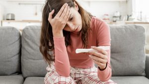 Frau schaut verzweifelt auf den Schwangerschaftstest