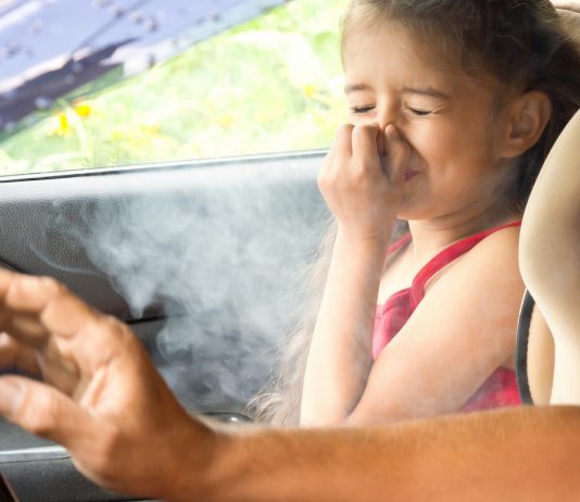 Vater raucht neben Tochter im Auto
