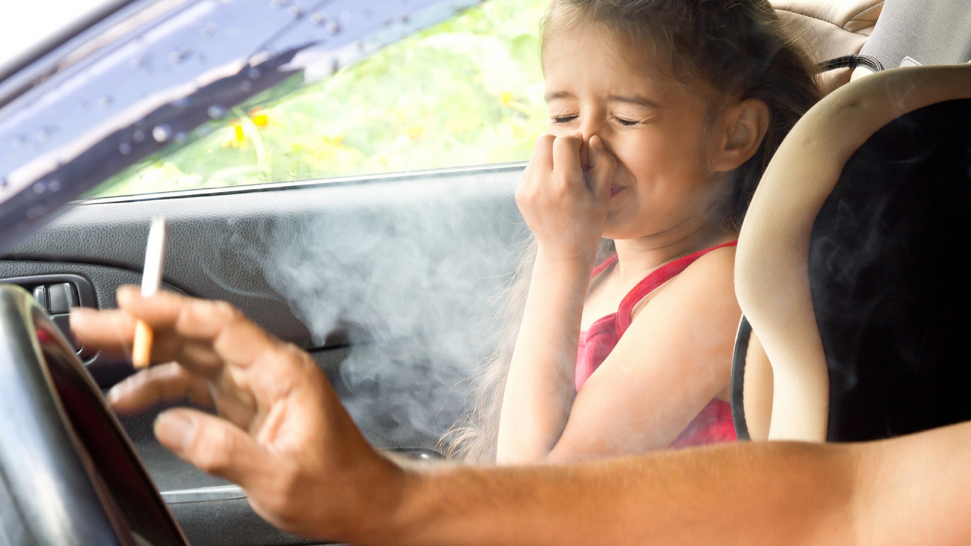 Vater raucht neben Tochter im Auto