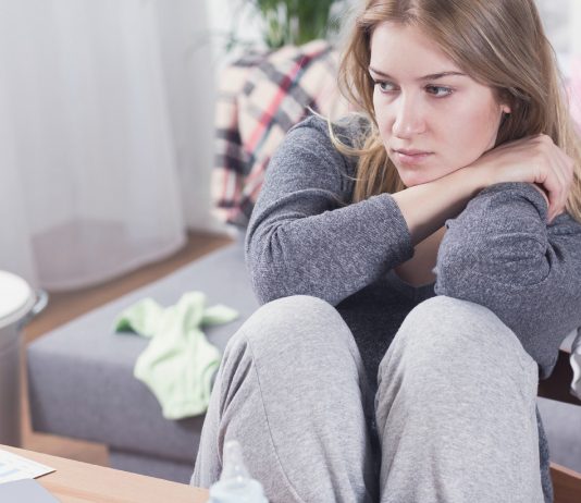 Mutter sitzt traurig und erschöpft in ihrer Wohnung