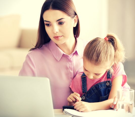 Mama sitzt mit ihrer Tochter vor dem Laptop