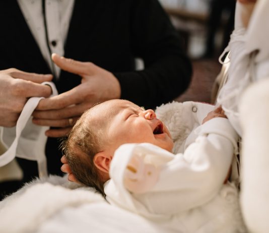 Kleines Baby weint bei der Taufe