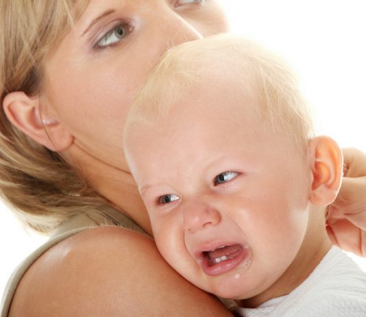 Baby weint auf dem Arm von seiner Mama