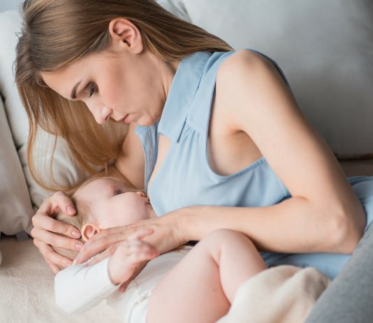 Mama stillt ihr Baby auf dem Sofa