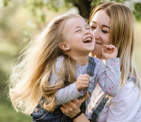 Mama spielt mit ihrer Tochter draußen im Sommer