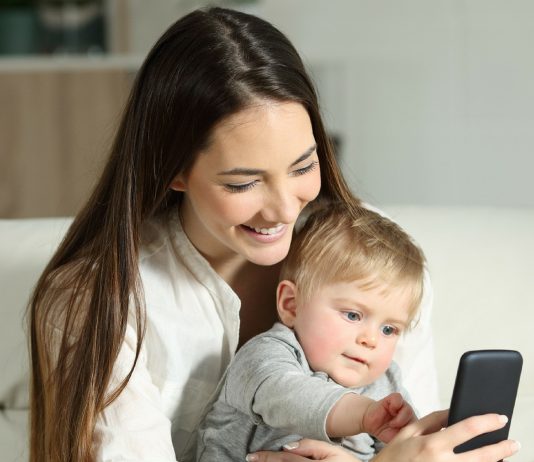 Kleinkind spielt am Smartphone von seiner Mama