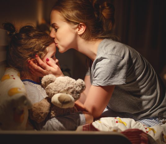 Mama bringt ihre Tochter liebevoll ins Bett