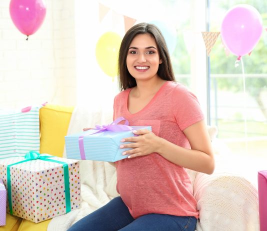 Schwangere Frau freut sich über ihre Geschenke