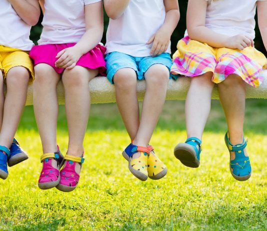 Kinder sitzen im Garten auf einer Bank