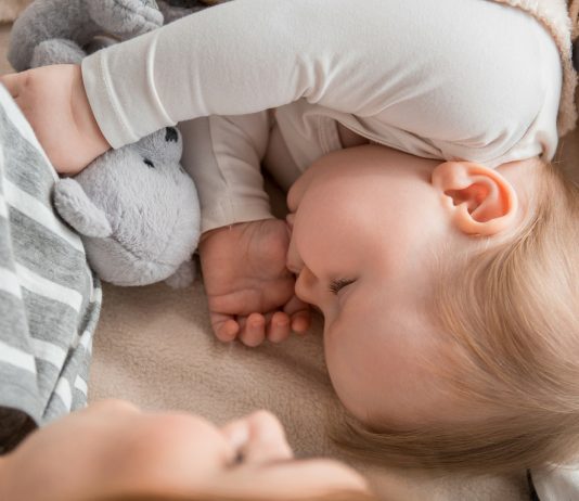 Baby schläft bei seiner Mama und seinen Kuscheltieren