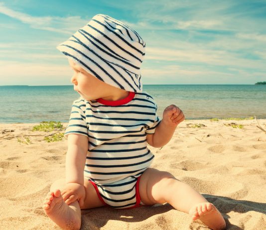 Baby mit Sonnenhut am Strand