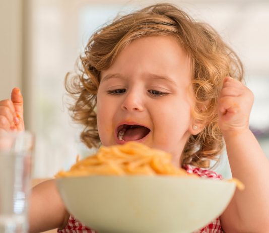 Mädchen sitzt wütend vor ihren Spaghetti