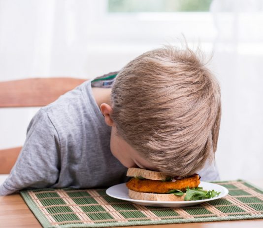 Junge schläft auf seinen Sandwich ein