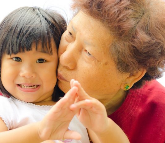 Asiatisches Kleinkind bekommt von seiner Oma einen Kuss
