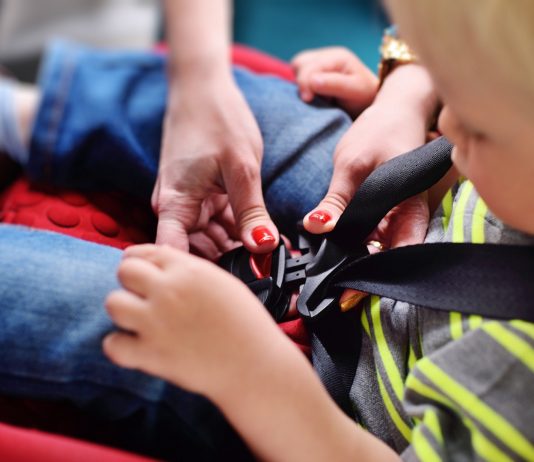 Junge wird im Kindersitz angeschnallt