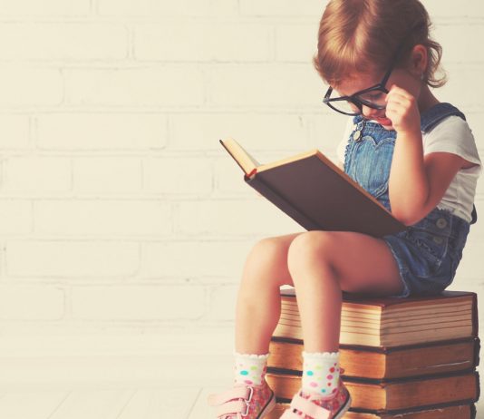 Kleines Mädchen liest ein großes Buch