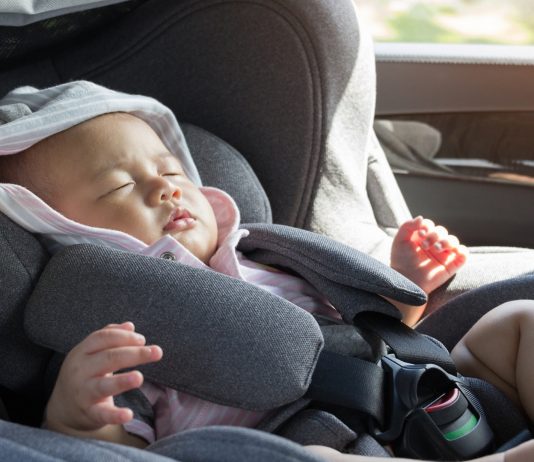 Asiatisches Baby schläft im Maxi Cosi