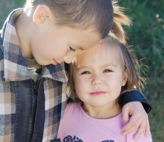 Großer Bruder umarmt seine kleine Schwester