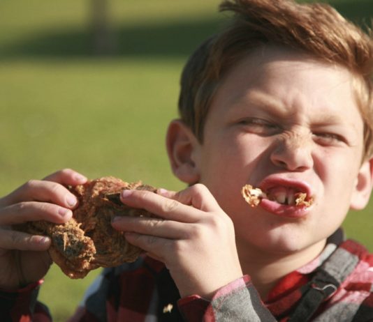 Junge isst Grillhähnchen