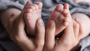 Impfungen schützen: Mamahände halten Babyfüße