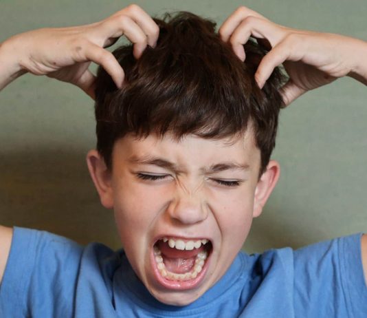Kopfläuse bei Kindern erkennen: Junge juckt sich den Kopf.