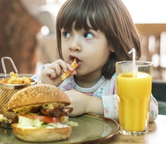 Kleines Mädchen isst Fast Food