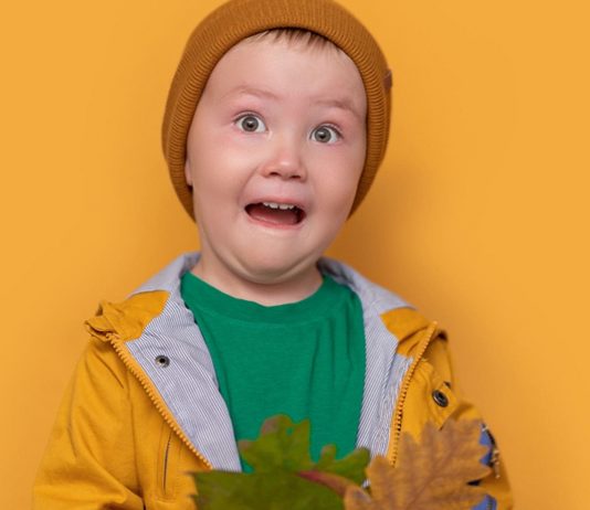 Herbst mit Kindern: Junge in Regenzeug schneidet Grimasse