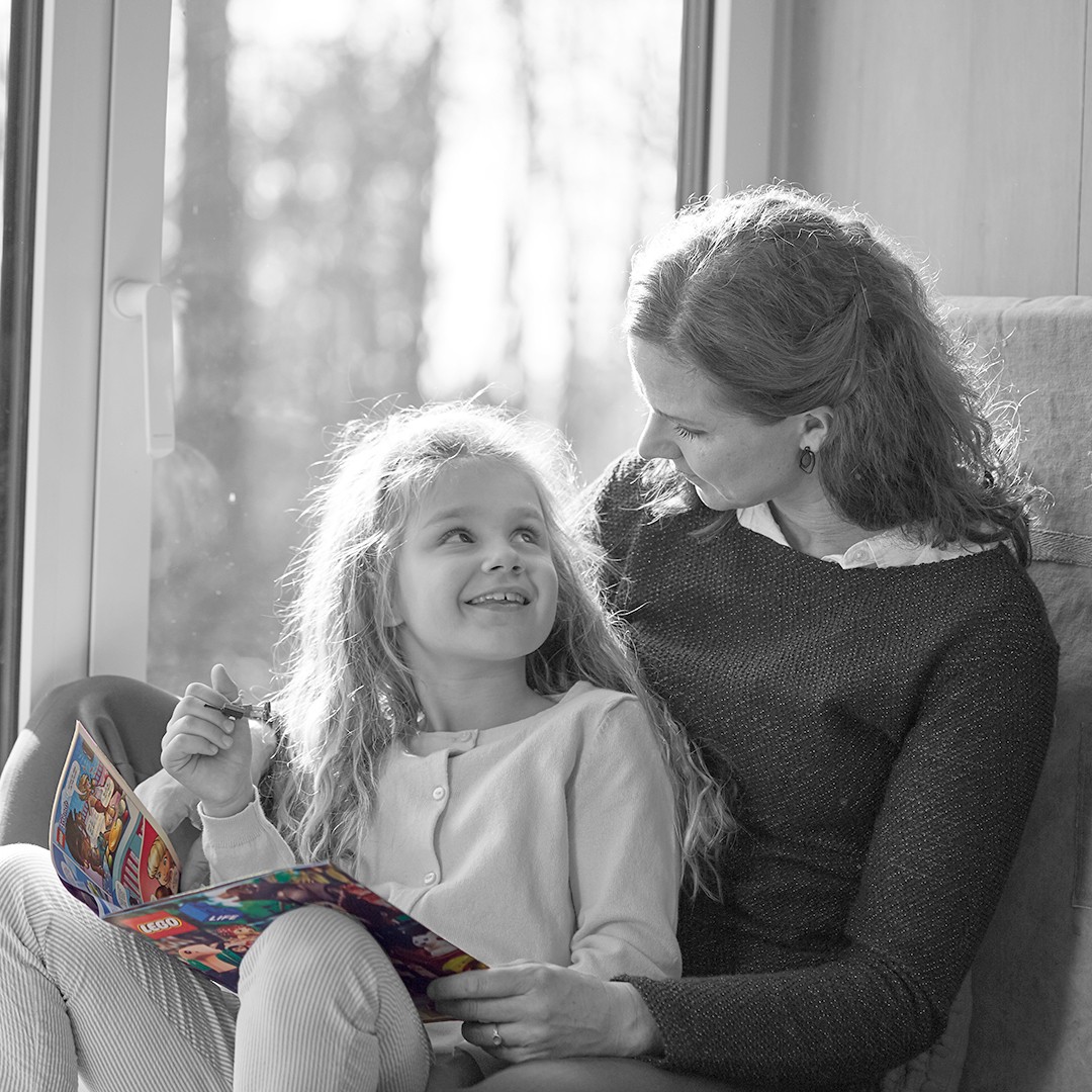 Mama und Tochter lesen und kuscheln.