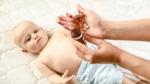 Mutter gibt Baby Globuli, um die Erkältung natürlich zu bekämpfen