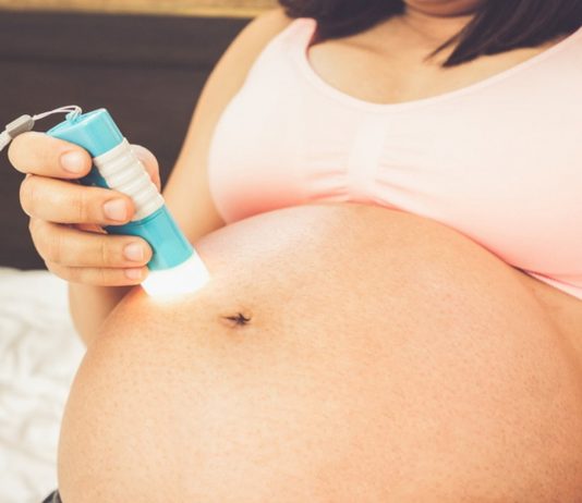 Baby in Beckenendlage zum Drehen bringen: Schwangere mit Taschenlampe