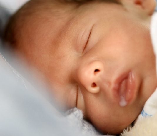 Einschlafstillen abgewöhnen: Schlafendes Baby mit Milchtropfen am Mund