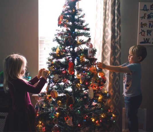 Christbaumschmuck Kinder basteln: Mädchen und Junge dekorieren Weihnachtsbaum