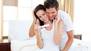 Paar freut sich ueber positiven Schwangerschaftstest