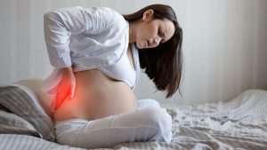 Schwangere mit Rueckenschmerzen, die bei einem Sternengucker Baby oft vorkommen