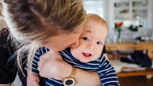 Silvester Angst Kleinkind: Mama hält Baby und küsst es auf die Wange.