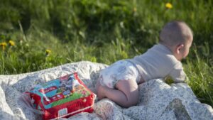 Baby krabbelt auf Decke im Freien.