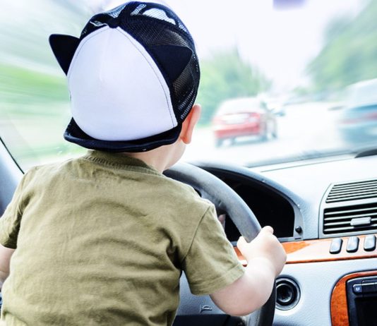 Ein kleiner Junge löste die Handbremse eines Autos.