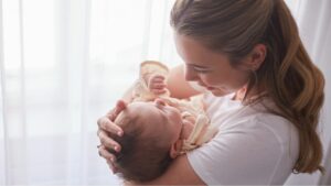 Eine Mama hat ein Baby auf dem Arm und kuschelt mit ihm.
