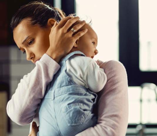 Mama ist müde und erschöpft, hält Baby im Arm