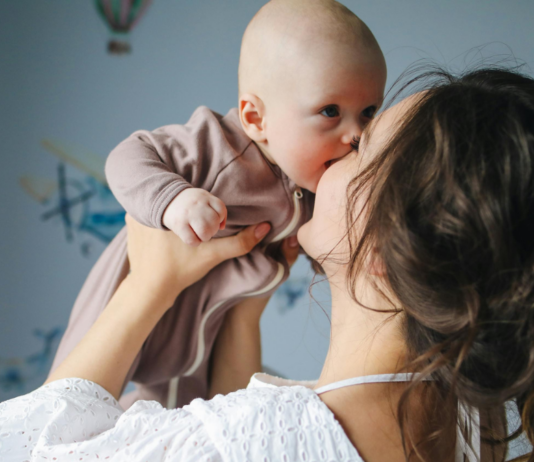 Mutter hebt Baby in die Luft und küsst es