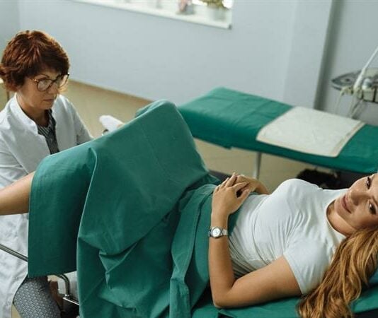 Frau auf dem gynäkolgischen Untersuchungsstuhl, während die Frauenärztin sie untersucht.