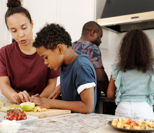 Familie steht gemeinsam in der Küche und kocht.