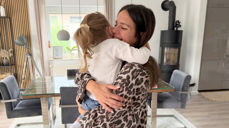 Mama umarmt ihre kleine Tochter und lacht dabei.
