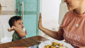 Mama und Kind klatschen sich am Esstisch ab.