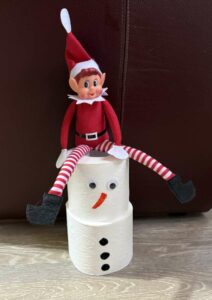 Der Elf on the Shelf hat sich einen Schneemann aus Klopapier gebaut.