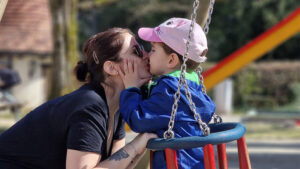 Sabrina küsst ihren erstgeborenen Sohn beim Schaukeln.