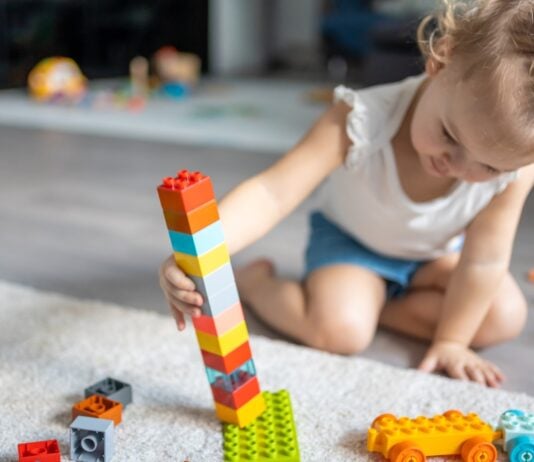 Mädchen baut selbständig einen Turm mit LEGO duplo.