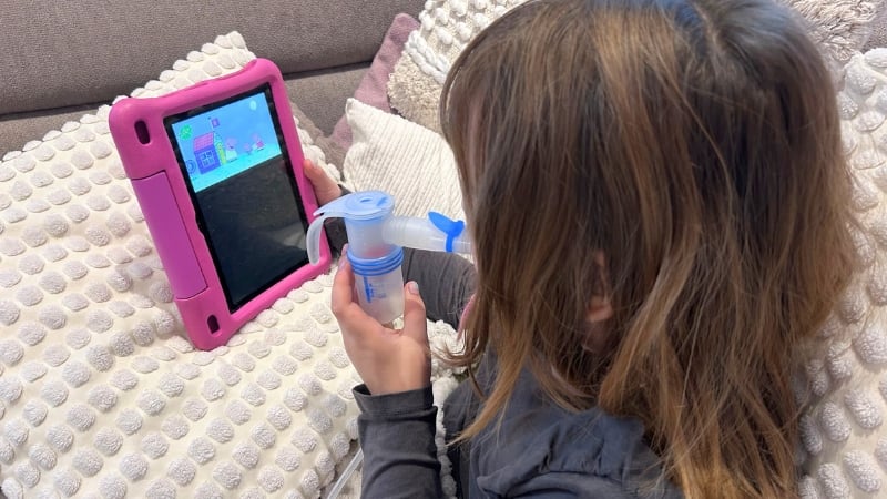 Mädchen inhaliert und schaut dabei eine Folge Peppa Wutz.